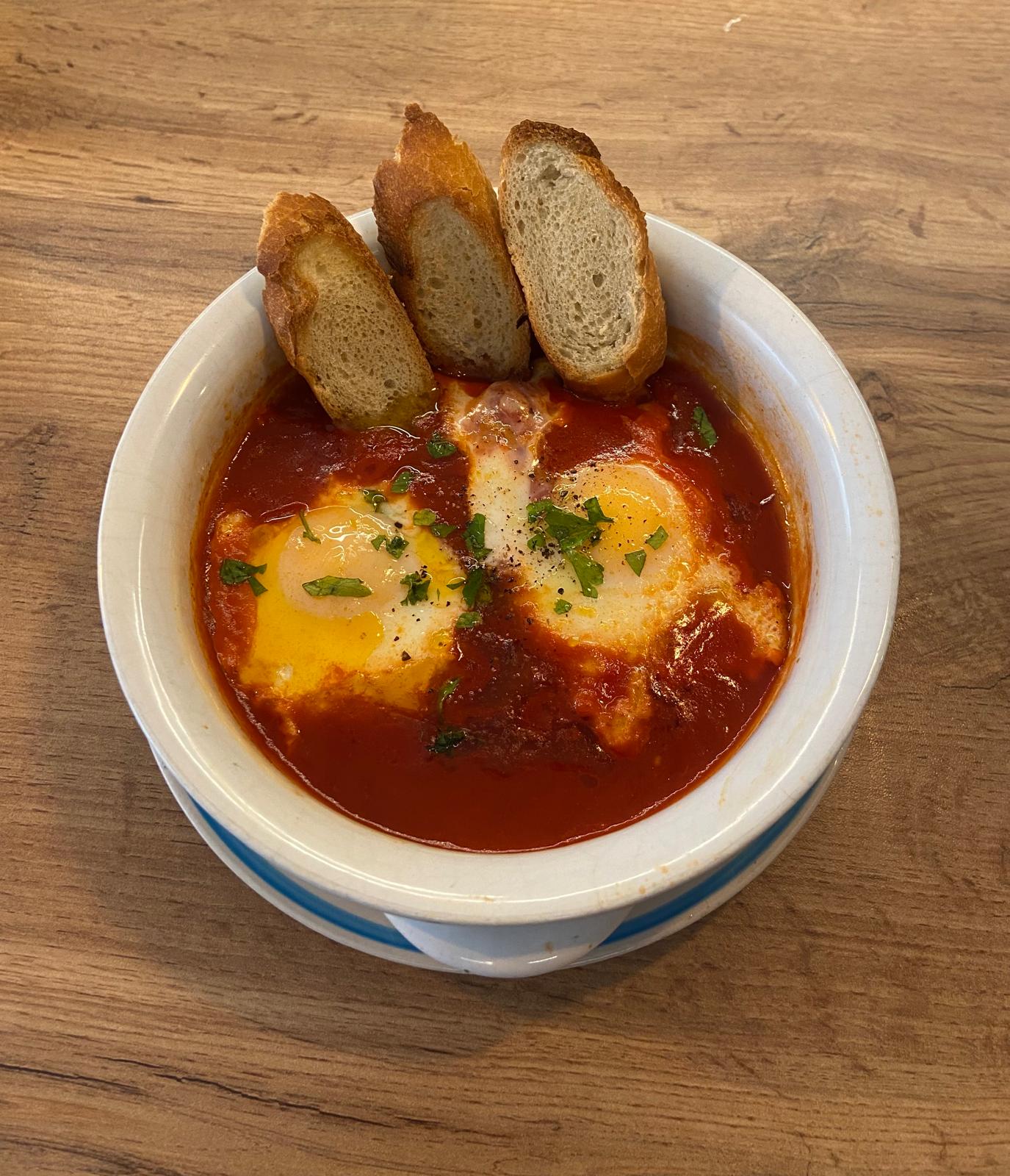 Uova shakshuka: uova, salsa di pomodoro speziata, pane tostato